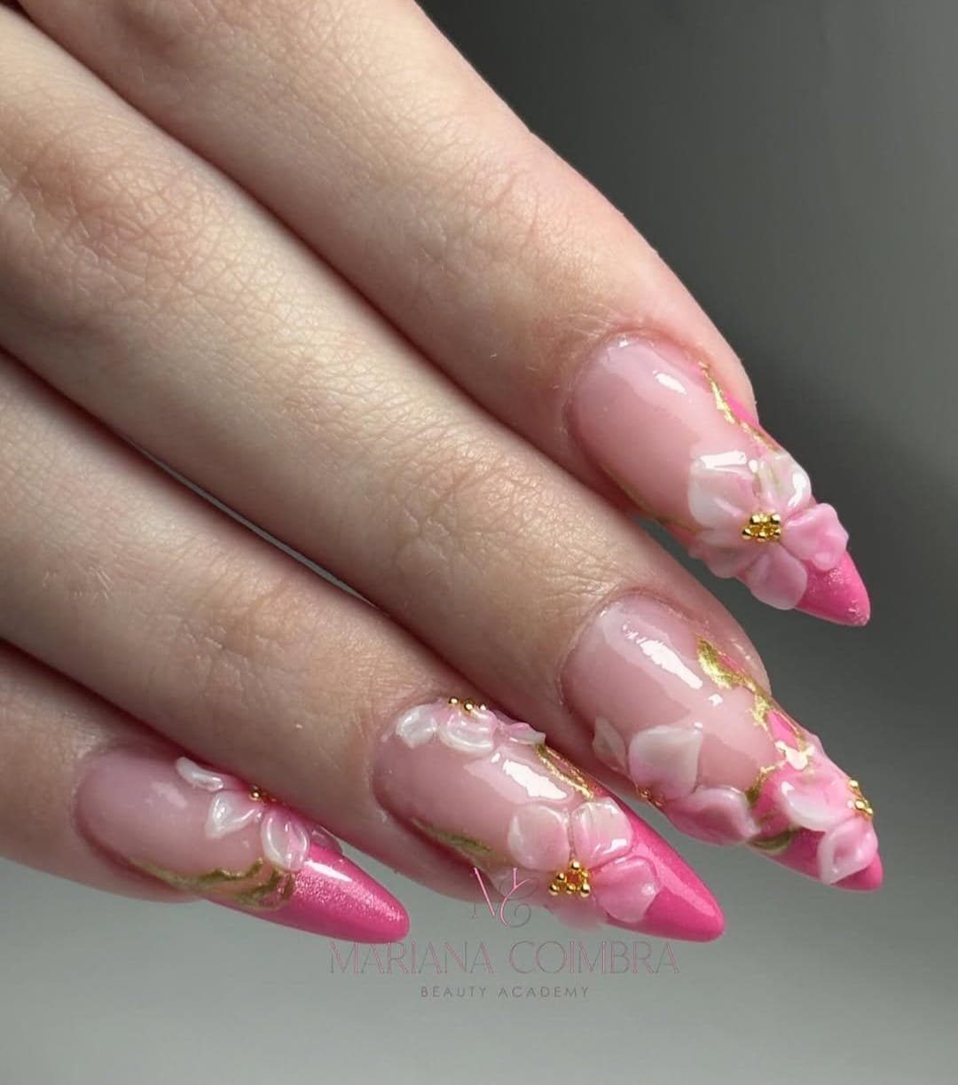 Unhas em amêndoa com base nude, flores 3D brancas e rosa com pormenores dourados