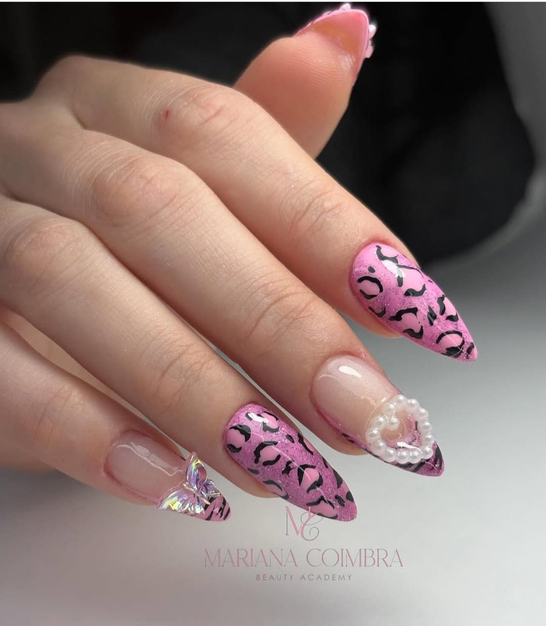 Unhas em amêndoa com animal print leopardo em rosa e preto, pérolas e borboleta em relevo