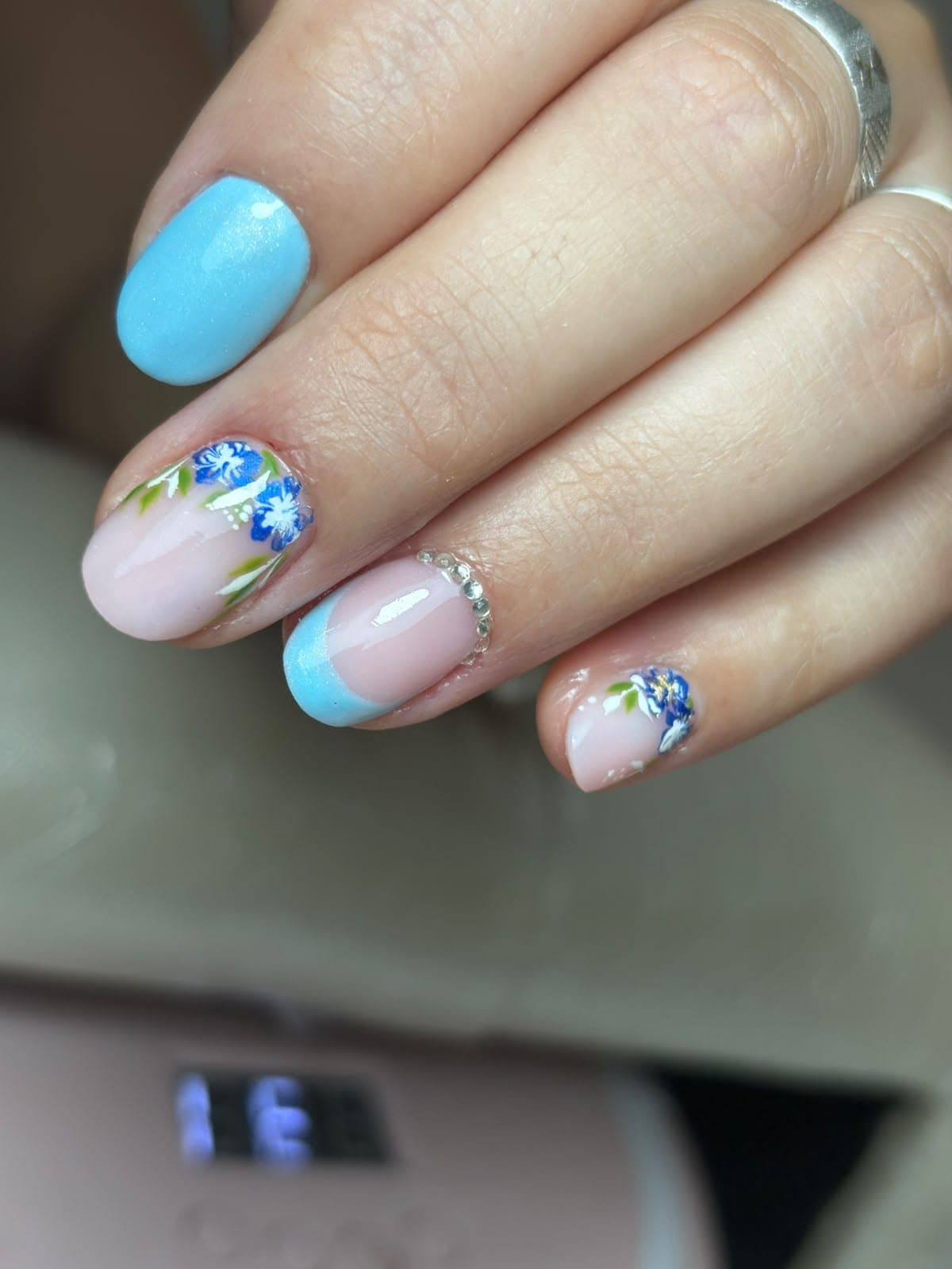 Unhas em amêndoa com base nude, ombré azul-claro nas pontas e linhas finas em glitter azul