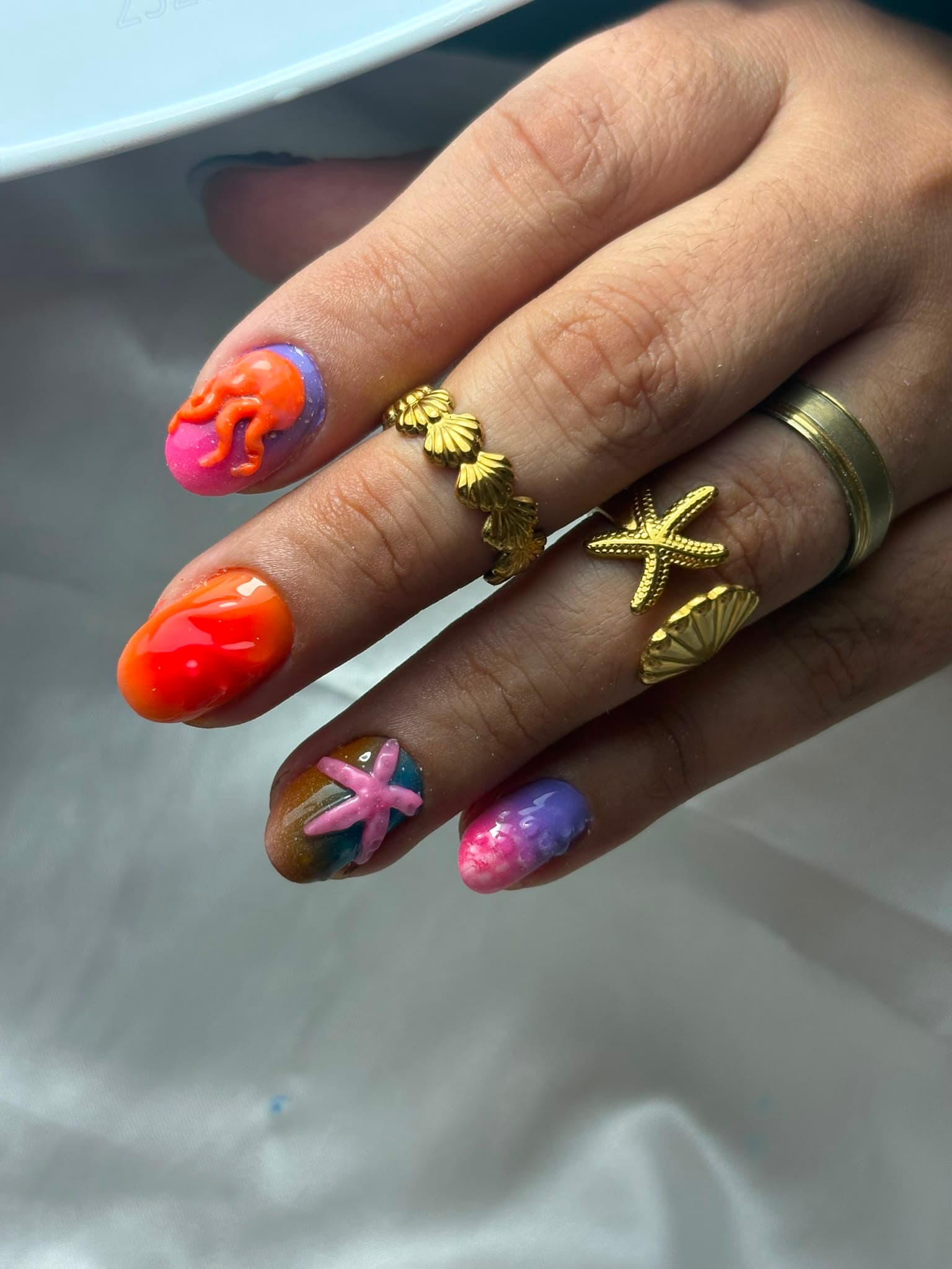 Unhas stiletto compridas com design degradê roxo e laranja, efeito marmoreado, aplicações 3D e strass