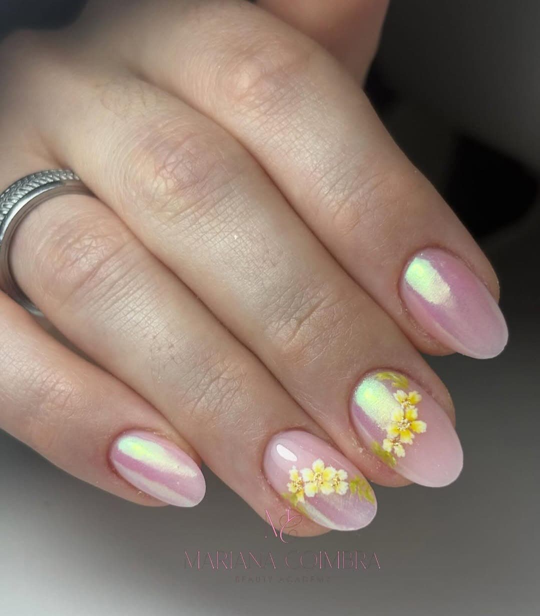 Unhas curtas ovais com efeito cromado holográfico e flores brancas e amarelas pressionadas